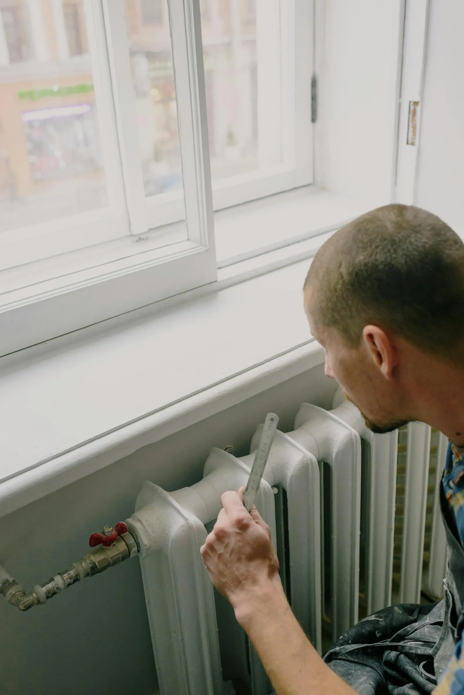 An engineer measuring a cast-iron radiator during a survey